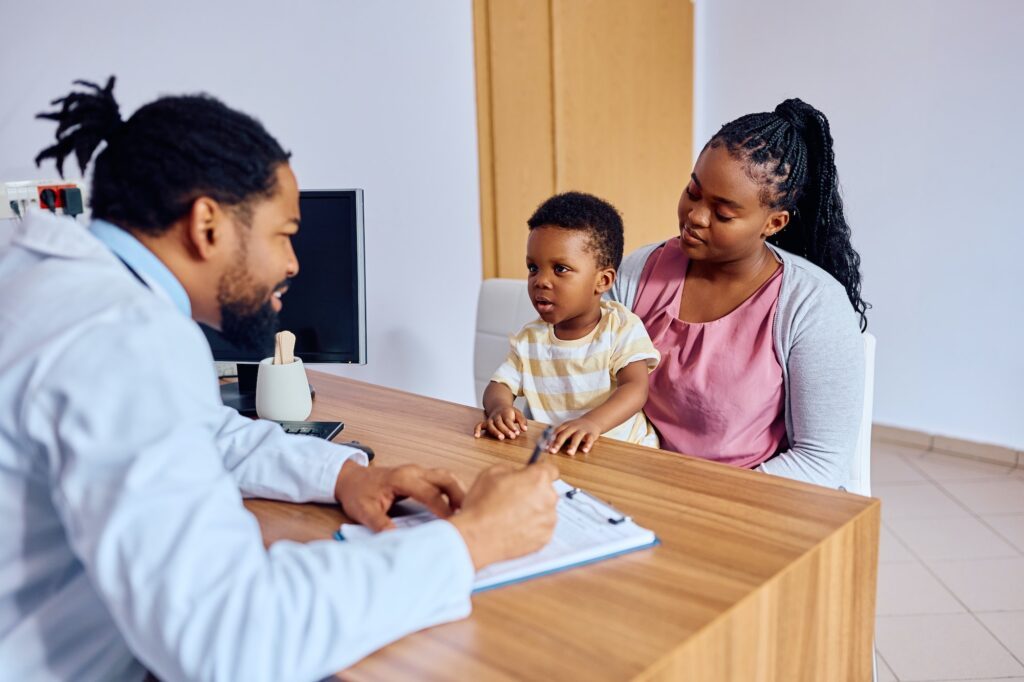 Cute black kid and his mother talking to a doctor at medical clinic.
