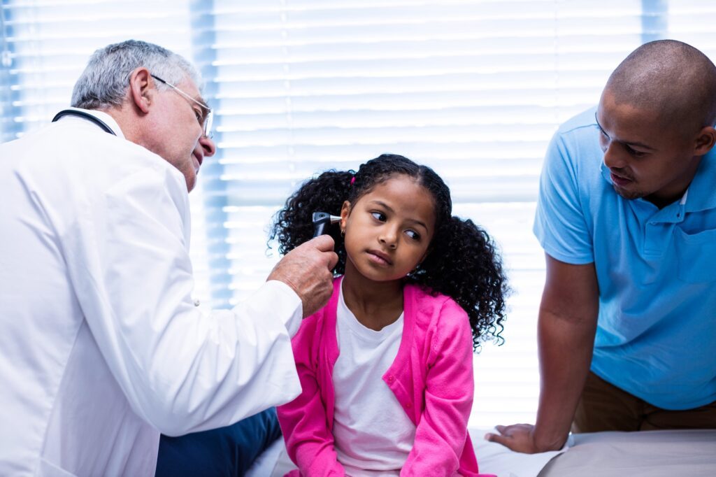 Doctor examining patients ear with otoscope