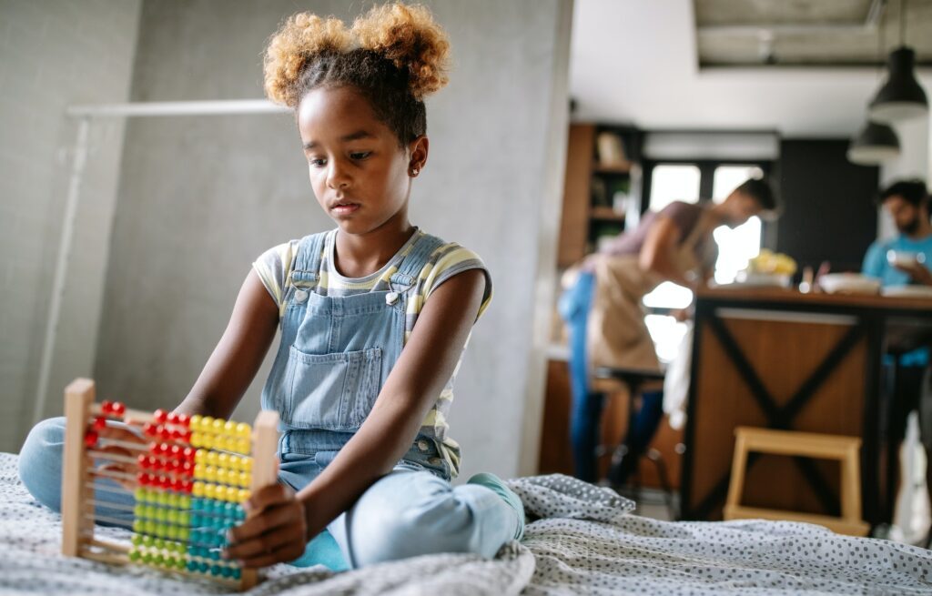 Happy african american kid girl learn to count at home with abacus