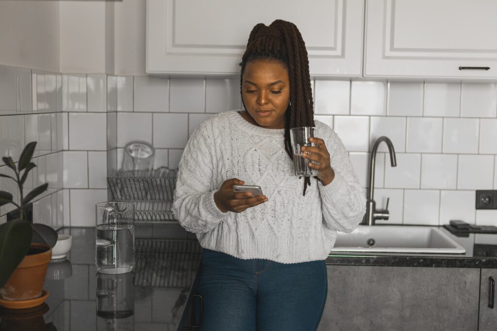 Portrait of African American female student dressed casually holding mobile phone and typing
