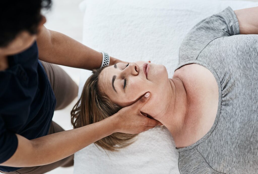 Shot of a mature woman getting her head and neck treated by a physiotherapist at a clinic